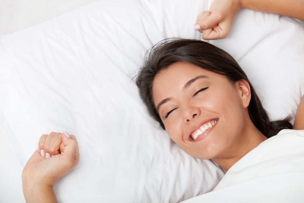 Beautiful woman awakening in her white bed and yawning