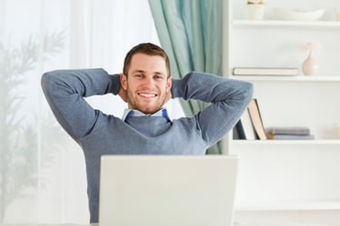 Smiling young businessman leaning back in his home office