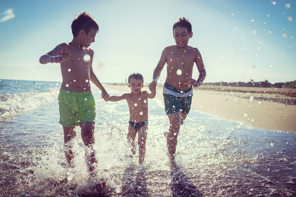 Kinder rennen am Strand durchs Wasser