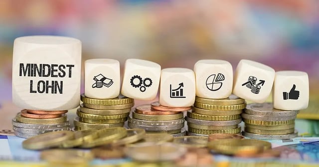 Würfel mit Schriftzug Mindestlohn auf Münzstapel