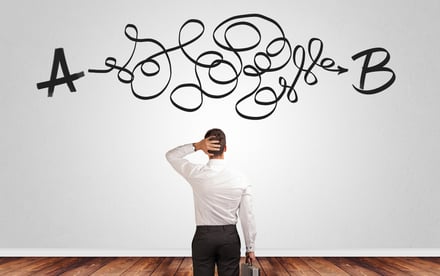 Businessman looking for connection between two things while standing in front of a wall