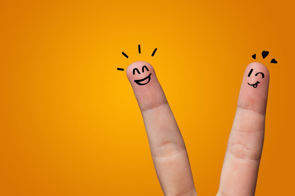Fröhliche Gesichter auf 2 Fingern auf orangem Hintergrund